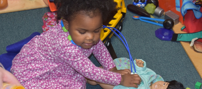 Young girl using stethoscope on baby doll