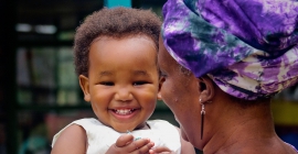 Young black child smiling while being held by adult